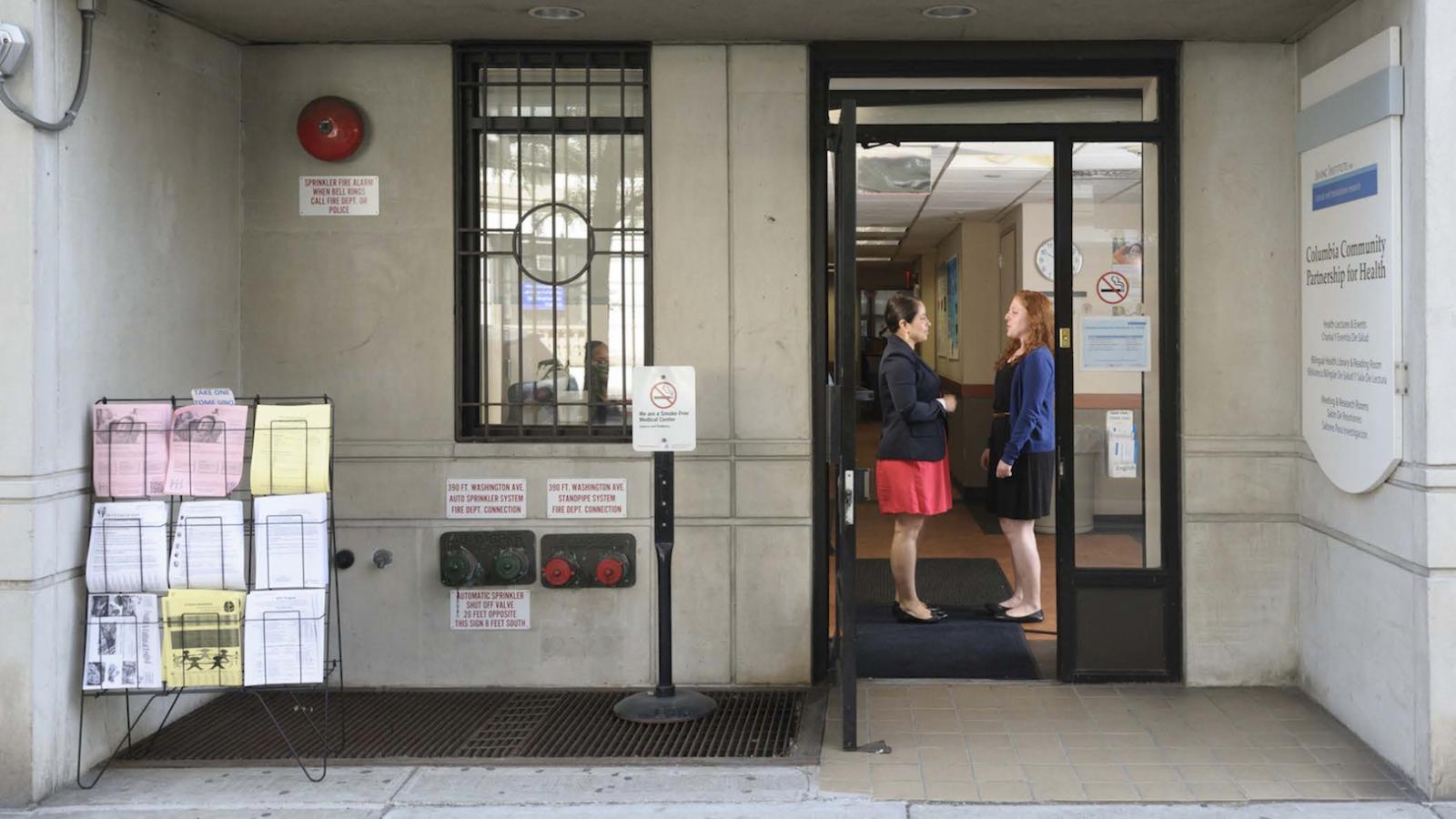 Two women stand in a doorway talking.