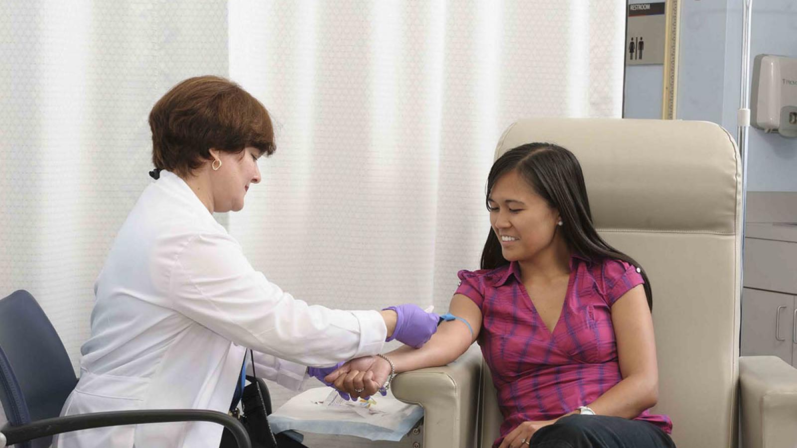Nurse draws blood from woman’s arm.