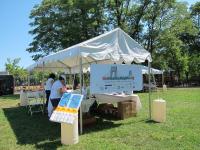 A white tent with people selling goods.