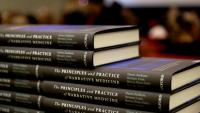 A stack of copies of the book "The Principles and Practices of Narrative Medicine"